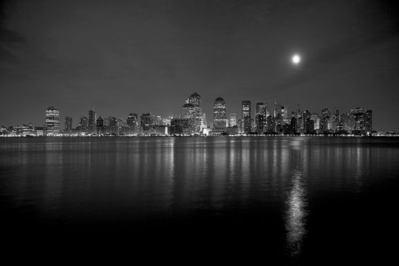 # Lune,8 Vue nocturne en noir et blanc d'une ville avec un ciel étoilé et le reflet sur l'eau.