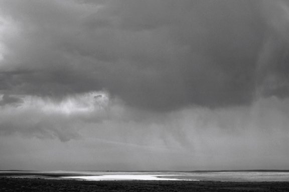 # Sombre Ciel nuageux avec des reflets sur une étendue d'eau sombre.